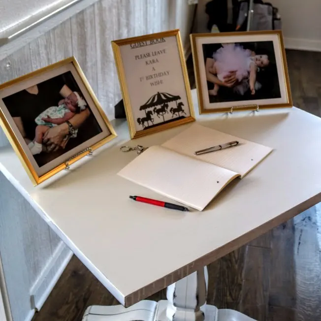 Gold framed monthly photos and Carousel themed notebook for guests to write 1st birthday wishes