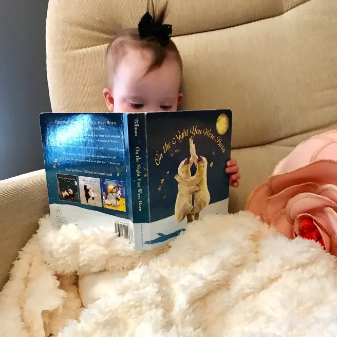 Kara holding one of her favorite books, On The Night You Were Born by Nancy Tillman